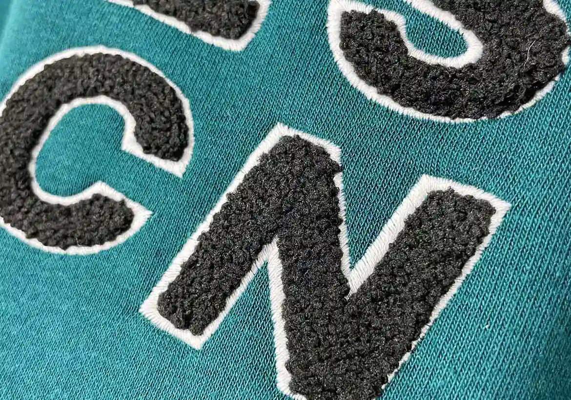Close-up of textured embroidery lettering on custom apparel, showcasing high-quality embroidery techniques for personalized clothing – Custom Apparel, Screenprinting, and Embroidery services in Los Angeles.